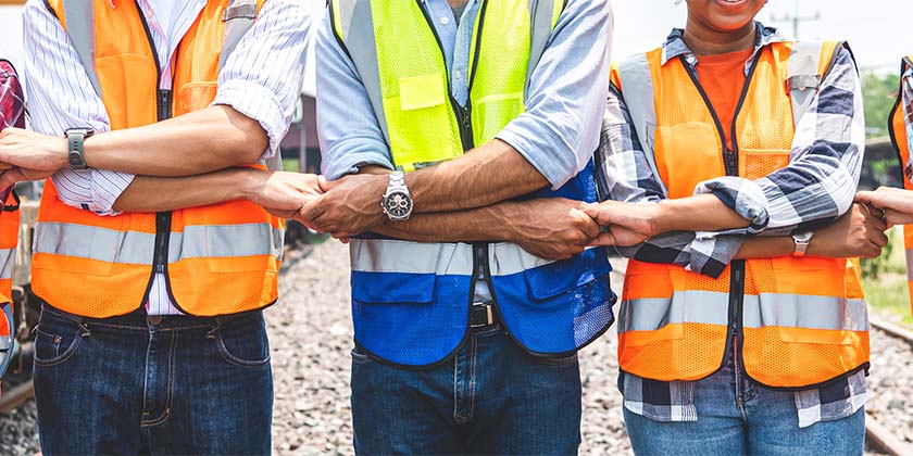 colaboradores equipados com EPIs de mãos dadas formando uma fileira