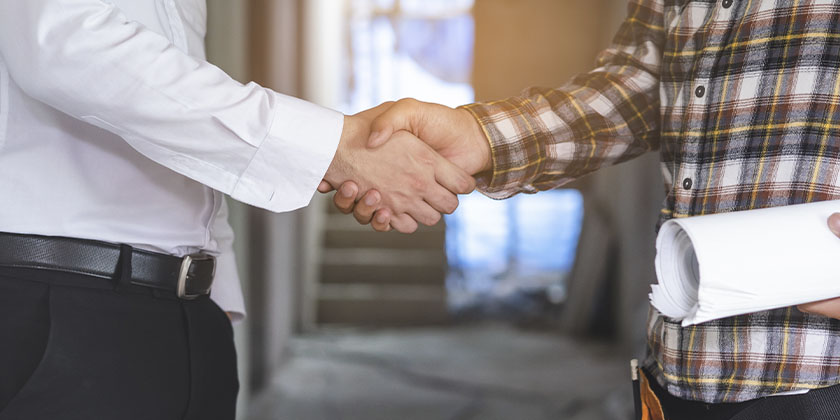 Empresário apertando a mão de um construtor que trabalhará em sua obra.